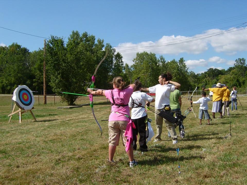 A group of people standing in the grass holding bows.
